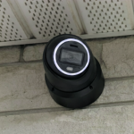 Outdoor dome camera under soffit monitoring entry.