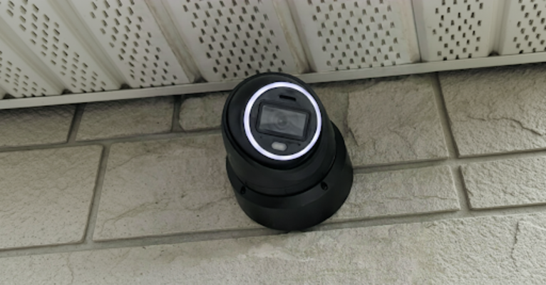 Outdoor dome camera under soffit monitoring entry.